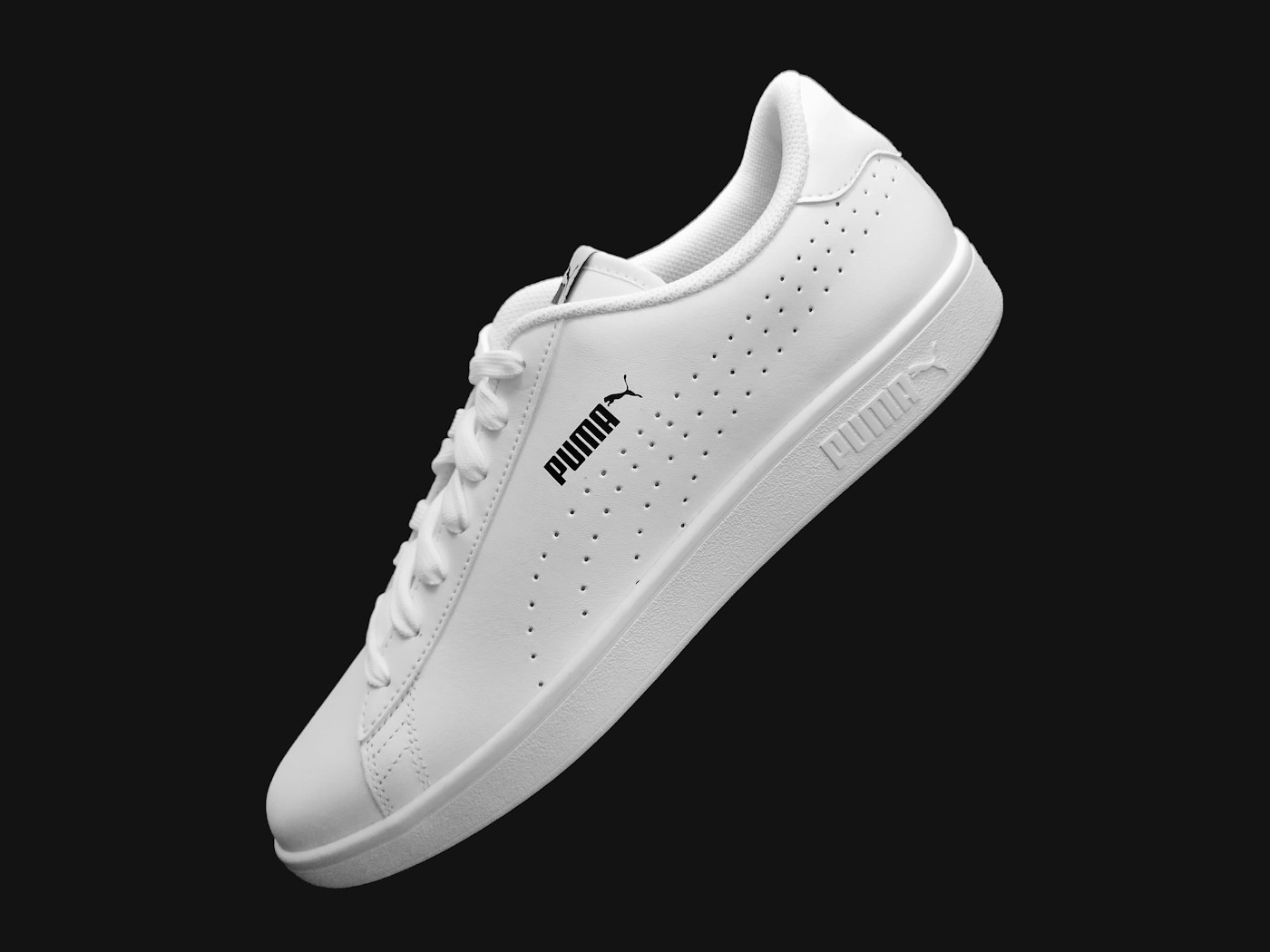 Tenis Puma branco em fundo escuro editorial